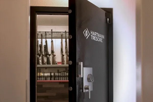 Geöffnete Tresortür von HARTMANN TRESORE mit Blick in einen Waffenraum mit Langwaffen an Wandhalterungen