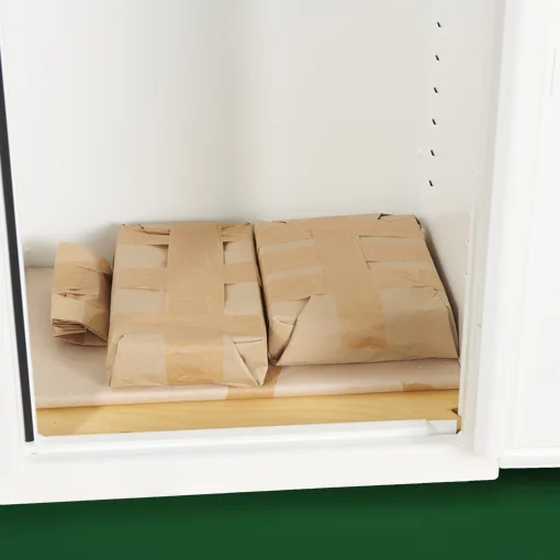 In Packpapier verpackte Teile auf dem Boden eines weißen Tresors – plastikfreie Verpackung der Serie GREENITY