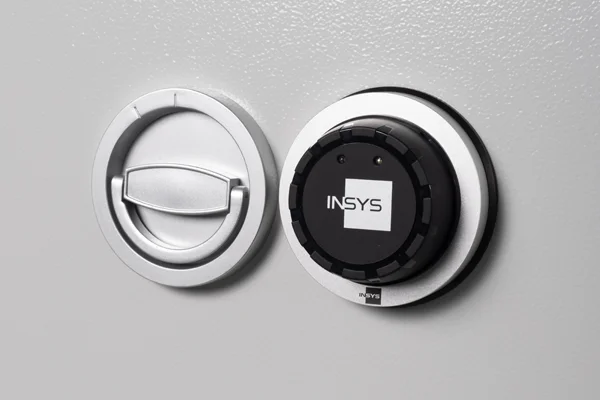 Elektronisches Tresorschloss E90300 von INSYS neben dem Klappgriff an einer hellgrauen Tresortür