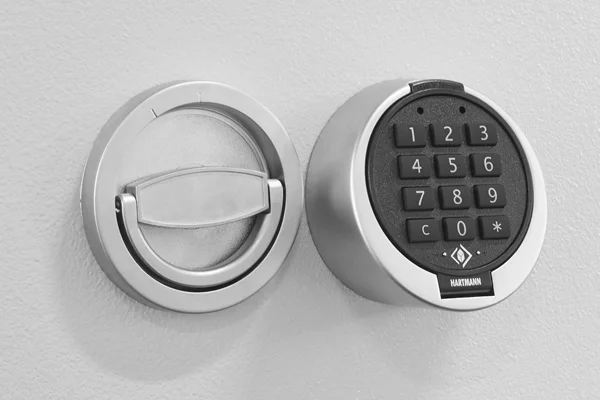 Rundes Elektronikschloss von HARTMANN mit Zifferntastatur neben einem Klappgriff an einer hellen Tresortür