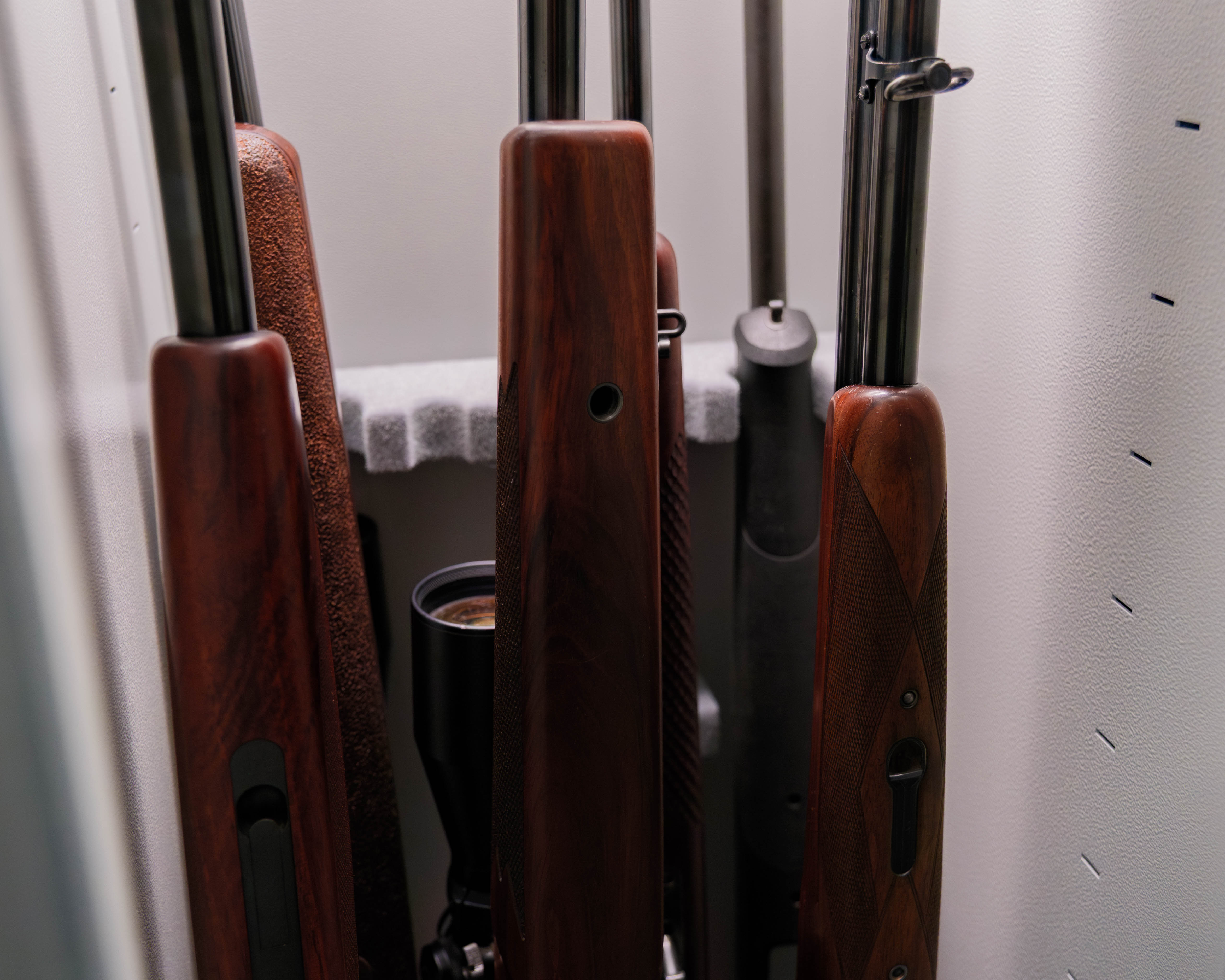 Langwaffen mit Holzschäften und ein Zielfernrohr stehen in der Gewehrhalterung eines Langwaffenschranks
