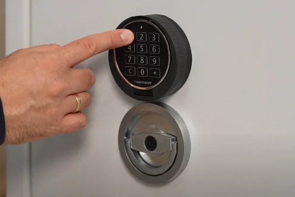Hand gibt einen Code am Elektronikschloss E70400 von WITTKOPP über dem Drehgriff einer Tresortür ein