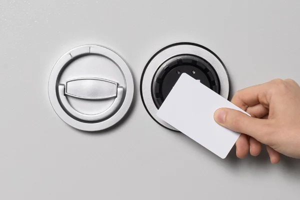 Hand hält eine RFID-Karte vor das Tresorschloss E90300 neben dem Klappgriff, um es zu öffnen