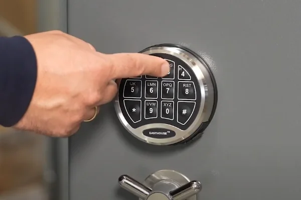 Person tippt einen Code in das elektronische Zahlenschloss eines Tresors der Marke EASTHOUSE