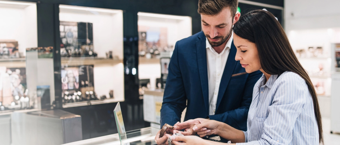 Frau und Mann betrachten an einer Verkaufsvitrine im Juweliergeschäft eine Armbanduhr