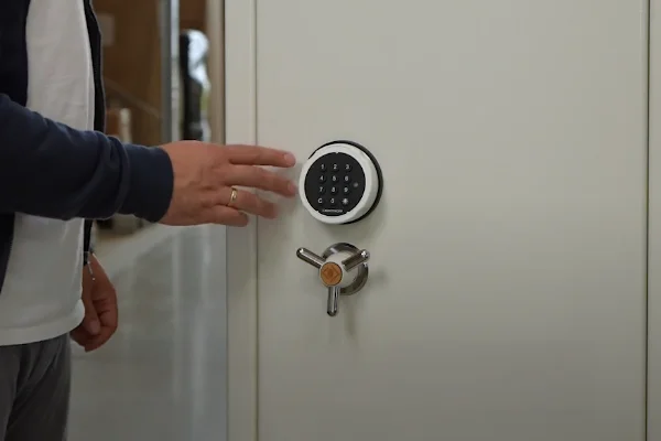 Person bedient das Elektronikschloss E73000 an einem hellen Tresor mit Dreisterngriff