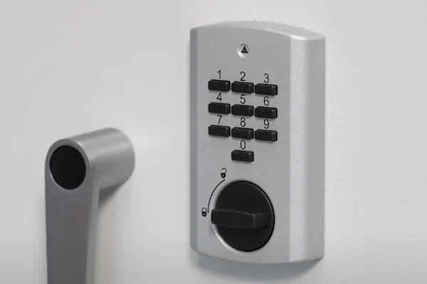 Nahaufnahme eines elektronischen Tastenschlosses mit Drehknauf neben dem Griff einer Tresortür